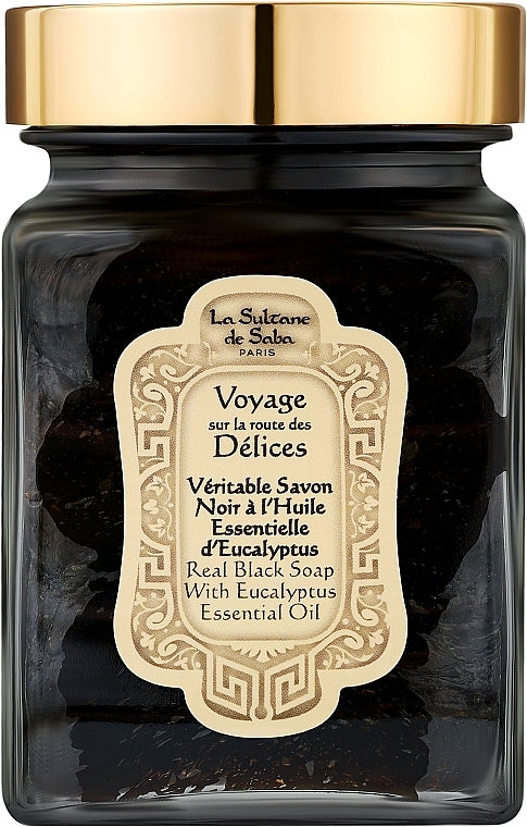 A glass jar of La Sultane de Saba Real Black Soap With Eucalyptus Essential Oil  Real Black Soap with Eucalyptus Essential Oil, featuring a shiny gold lid and a beige label.
