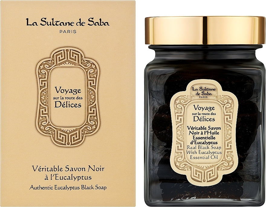 La Sultane de Saba Real Black Soap With Eucalyptus Essential Oil Authentic Eucalyptus Black Soap shown in a dark glass jar with a gold lid next to its beige packaging box.