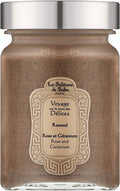 A jar of La Sultane de Saba Paris 'Rassoul' body scrub, featuring a speckled brownish-beige scrub inside a clear glass jar with a metallic silver lid and a cream-colored decorative label. Rassoul Face, Body & Hair Mask
