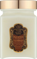 A jar candle with a frosted glass body showing a warm cream-colored wax, topped with a metallic rose gold lid. The front features an ornate gold and dark brown label for 'La Sultane de Saba' 'Voyage sur la route des Epices' (Shea Butter Spice Journey).